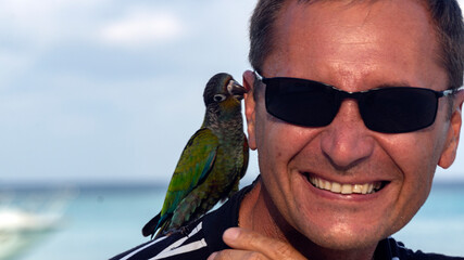 Photo shoot of a young man on the beach with a parrot. 