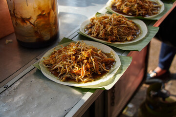 Close-up of Char Kway Teow, a popular Malaysian street food, served on banana leaves. The dish...