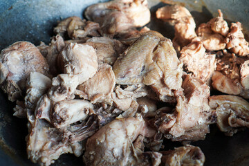 Close-up view of cooked chicken pieces in a dark wok. The chicken is light brown and appears tender. Close-up of Cooked Chicken Pieces in a Wok.