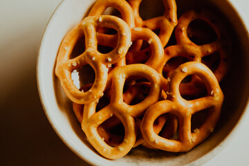 Salted mini pretzels are arranged in a white dish. Homemade, delicious pastries.