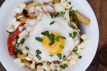 Closeup view of fried potatoes with melted cheese, chorizo, bell pepper, onion and a grilled egg in...