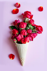 bouquet of red roses with white gypsophila in waffle ice cream cone cup on pink background