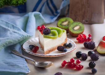 Slice of cheesecake decorated with kiwi, currants, and redcurrants