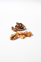 Group of peeled walnuts and their shells behind on a white background