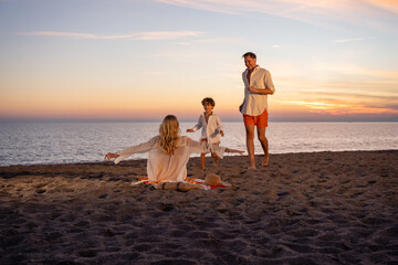 A happy family enjoying time together at the beach during sunset, playing and having fun.