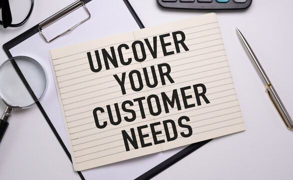 Uncover your customer needs text on white notepad, Business concept.