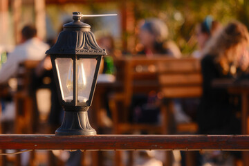 A night-light lantern stands on the fence outside the cafe