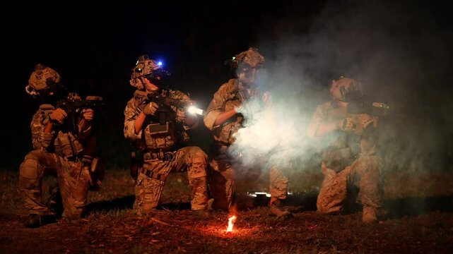 Soldiers in camouflage uniforms aiming with their rifles ready to fire during Military Operation at night