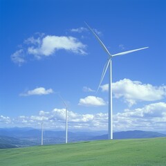 Wind turbines on a green hill under a blue sky with clouds.