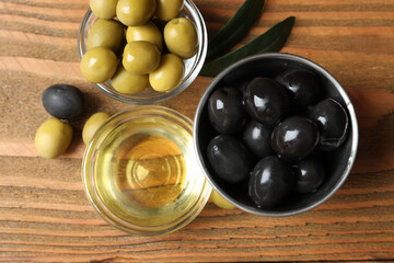 Bowl of fresh olive oil and olives with leaves on the table 