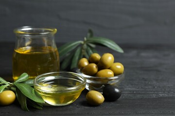 Bowl of fresh olive oil and olives with leaves on the table 