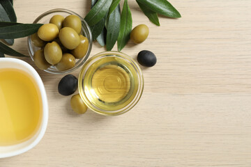 Bowl of fresh olive oil and olives with leaves on the table 