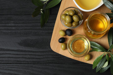 Bowl of fresh olive oil and olives with leaves on the table 