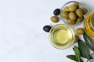 Bowl of fresh olive oil and olives with leaves on the table 