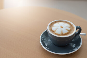 Hot coffee latte with latte art milk foam in cup mug on wood desk.