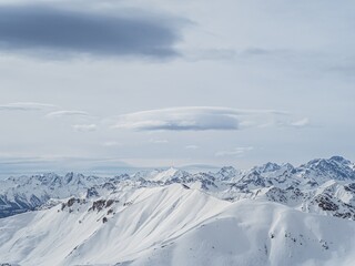 Obraz premium Snow-covered alpine peaks under cloudy sky