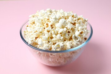 Delicious popcorn in a bowl on a colored background