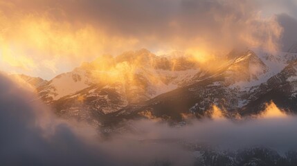 Fototapeta premium photograph of Snowy mountain range at sunset, glowing with golden hues and misty clouds