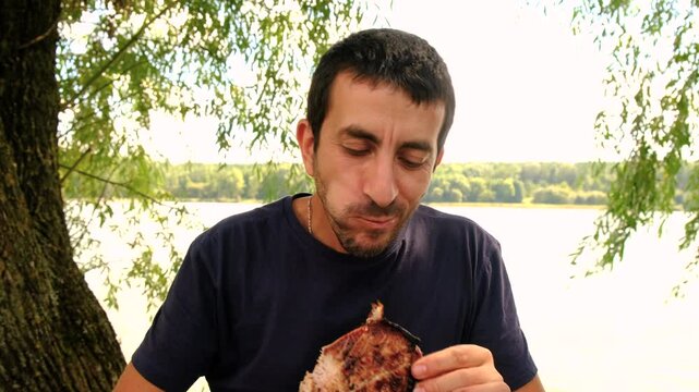 A man roasts meat on a fire outdoors. Elective focus.