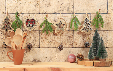 Empty wooden table with Christmas trees, kitchen utensils and holiday decorations on light background. Christmas and New Year mockup for design and product display, minimal Merry Christmas concept,