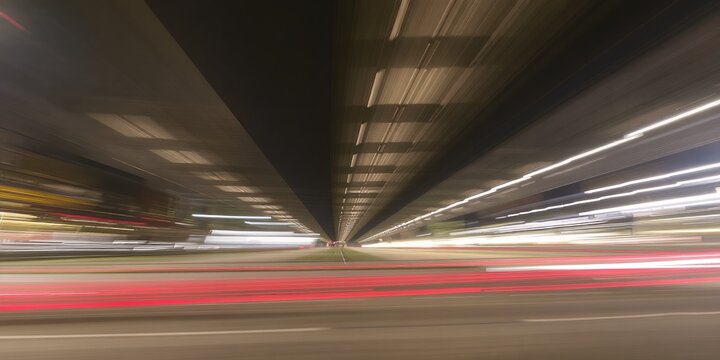 Dynamic lights create a streaking effect under a modern overpass at night