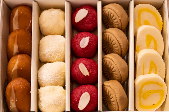 Assorted indian sweet box include Cream Gulab Jamun, Motichoor Laddu, GURER SONDESH, Cake Barfi, Balushai, Balushahi top view of pakistani and bangladeshi mithai dessert