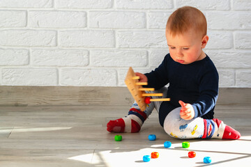 Little infant plays with wooden toys. The child collects a sorter. Educational logic toys for...