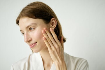 Medium close up of Caucasian lady touching soft cheek skin