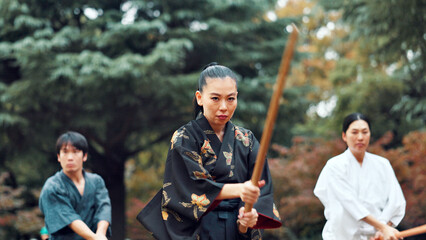 Martial arts, park and instructor with wood sword for fight, battle and samurai training class. Woods, ninja and mentor with bamboo weapon, kendo and warrior in autumn in Japan with fighter group © peopleimages.com