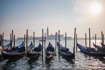 G&oacute;ndolas cl&aacute;sicas flotando en el Bacino di San Marco, el ic&oacute;nico puerto de Venecia, con vistas a la plaza y la bas&iacute;lica de San Marcos.