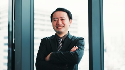 Fototapeta premium Happy, crossed arms and portrait of businessman in office with confidence for finance career. Smile, pride and Japanese male financial manager with positive attitude for company revenue in workplace.