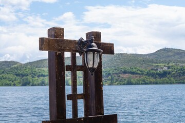 A beautiful antique lantern on a wooden lattice on the shore of a mountain lake.