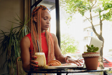 African woman entrepreneur in cafe with laptop