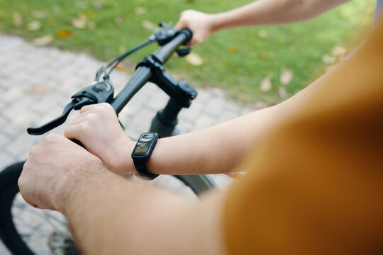 Close-up of grandfather helping his little grandson to ride a bike outdoors