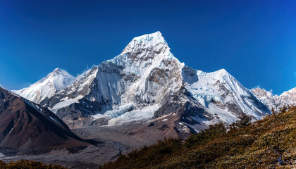 Obraz premium Majestic snow-capped peaks of Mount Everest rise against a brilliant blue sky in the Himalayan mountain range.