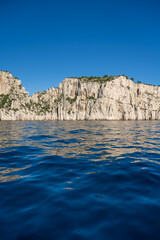 View from the Mediterranean Sea to the rocky coast of the Calanque National Park on a sunny summer day.