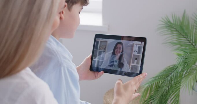 Young mother with child boy listening recommendations and appointment having online video call with doctor using tablet at home. Telemedicine and patient consultation online concept. 4k video.