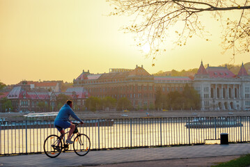 Naklejka premium Person riding a bike in the park against old city view