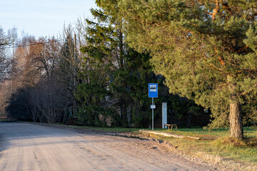 bus stop with sign in Latvia countryside on gravel road, trees on road sides