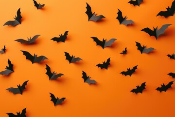 Fototapeta premium Orange Halloween background with black paper bat silhouettes.
