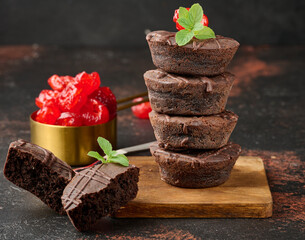 Chocolate brownies stacked, with the top adorned by a juicy red cherry and mint leaves