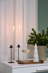  Christmas decor. This stylish decor includes elegant candles, a wine glass, pine branches in vase with lights.