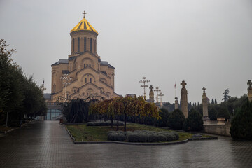 Fototapeta premium Autumn hues frame the majestic cathedral in Tbilisi, Georgia, inviting peaceful reflection and serene walks.