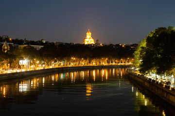 Obraz premium Glistening lights reflect on the river as Tbilisis vibrant nightlife showcases its stunning architecture.