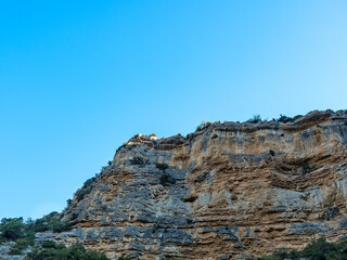 Fototapeta premium the imposing rocky gorges around Nyons in France, with their interesting horizontal stripe structure with shades of blue and reddish against a blue sky at sunrise