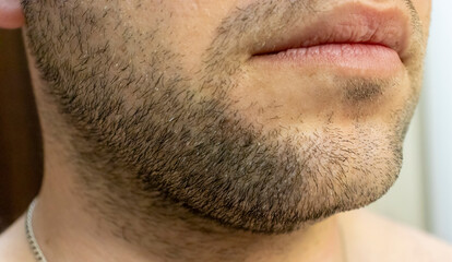 Fototapeta premium Close-up of a man's facial hair and lips, showcasing the texture and detail of his beard. Perfect for grooming or personal care themes.