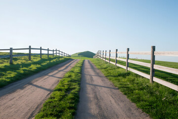 Fototapeta premium A dirt path leads to a hill under a tranquil blue sky