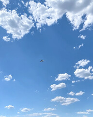 Fototapeta premium Airplane flying in blue sky with scattered clouds