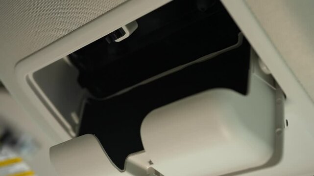 Woman driver opening car roof headliner box and taking glasses out of it. Vehicle top ceiling glasses box being open and used. Close up.