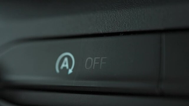 Woman's fingers activate or deactivate controls of vehicle's automatic engine start stop system. Designed to prevent idling and reduce fuel consumption and emissions, ecological and ecology concept.